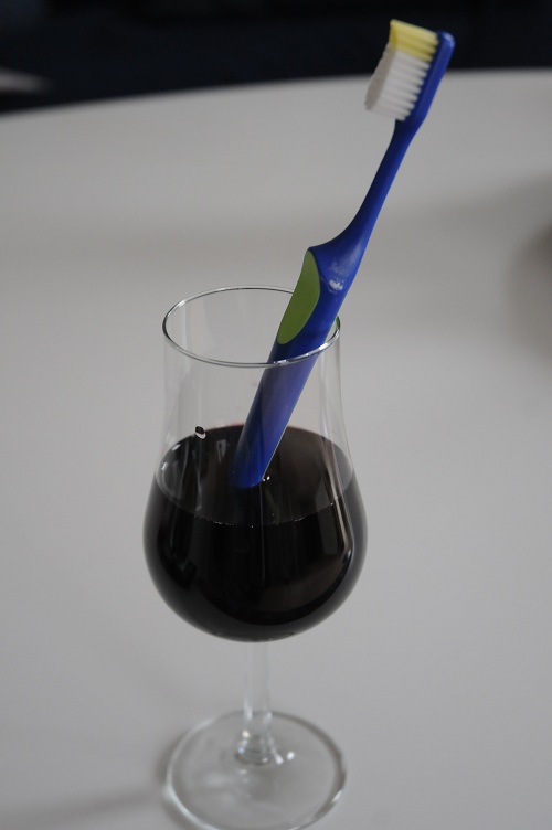 Glas rött vin med tandborste i